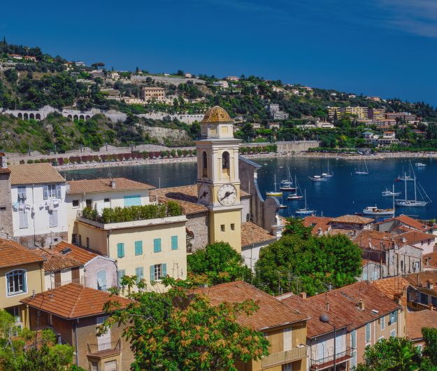 Brown and white concrete buildings near body of water under blue